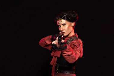 selective focus of steampunk woman aiming with gun to camera isolated on black clipart