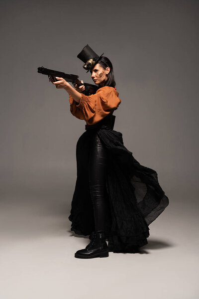 Вид в полный рост привлекательной стемпанк-женщины, держащей парня на сером
