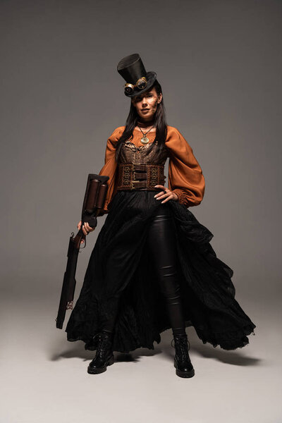 Вид в полный рост привлекательной стемпанк-женщины, держащей парня на сером
