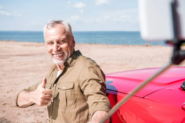 Χαμογελαστός Ανώτερος Άνθρωπος Στέκεται Κοντά Στο Κόκκινο Αυτοκίνητο Και Παίρνει — Φωτογραφία Αρχείου
