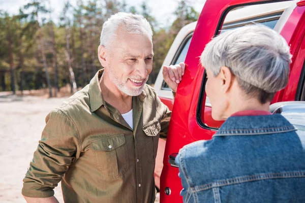 Lächelndes Seniorenpaar Steht Neben Rotem Auto Und Schaut Sich — Stockfoto