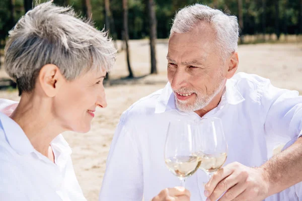 Seniorenpaar Klappert Weingläser Mit Wein Und Blickt Sich Lächelnd — Stockfoto