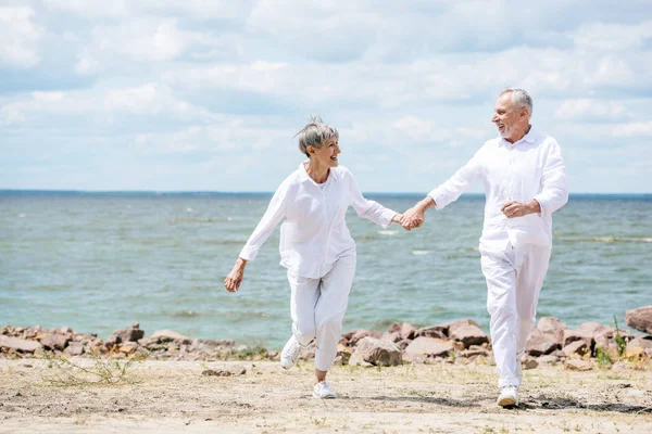 老年夫妇手牵手 在沙滩上互相看着对方的全长视图 — 图库照片