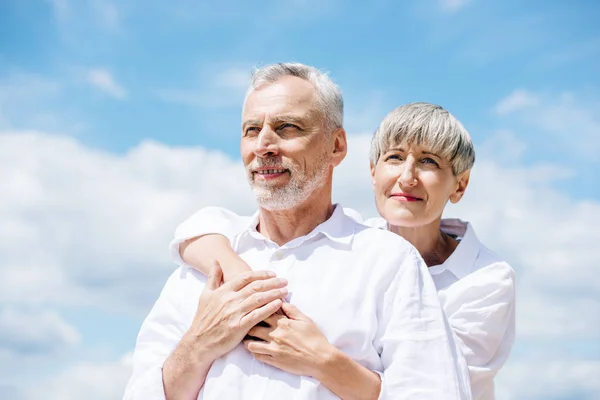 Happy Senior Couple White Shirts Embracing Blue Sky — Stock Photo, Image