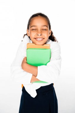 happy african american shoolgirl holding books and smiling with closed eyes on white background clipart