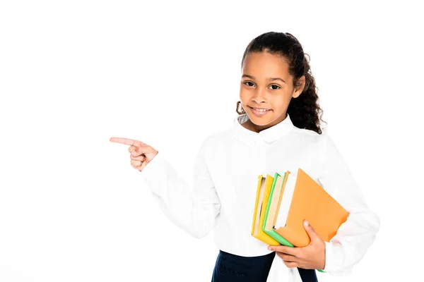 Alegre Afroamericana Colegiala Apuntando Con Dedo Mientras Sostiene Libros Aislados — Foto de Stock