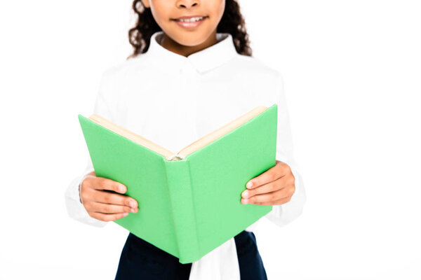 обрезанный вид улыбающейся африканской школьницы с книгой, изолированной на белом
