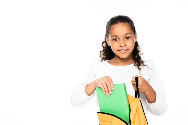 Adorable African American Schoolgirl Putting Book Backpack While Looking Camera — Stock Photo, Image