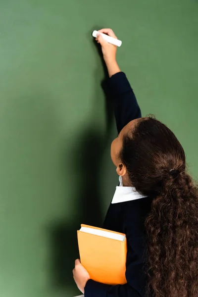 Back View African American Schoolgirl Writing Chalkboard While Holding Book — Stock Photo, Image
