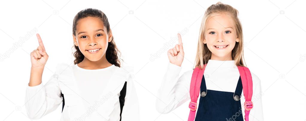 panoramic shot of two cute multicultural schoolgirls showing idea gestures isolated on white