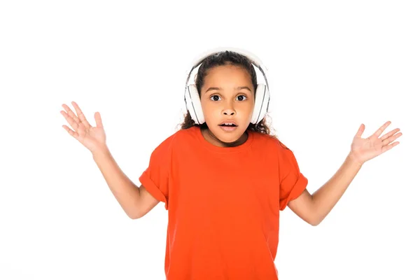 白で隔離されたヘッドフォンで音楽を聴きながらシュラッグジェスチャーを示す驚いたアフリカ系アメリカ人の子供 — ストック写真