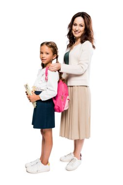 happy mother touching backpack of daughter isolated on white