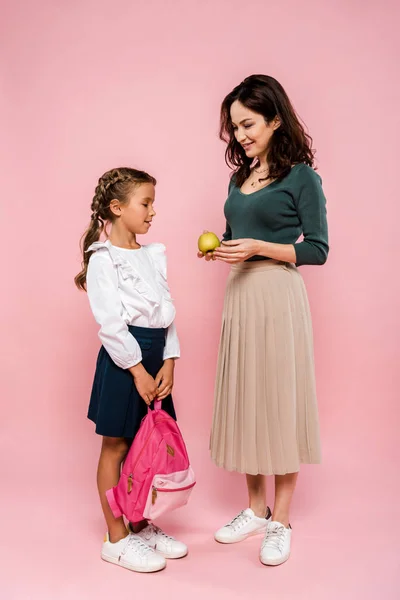 Mutter Hält Leckeren Apfel Neben Tochter Mit Rucksack Auf Rosa — Stockfoto