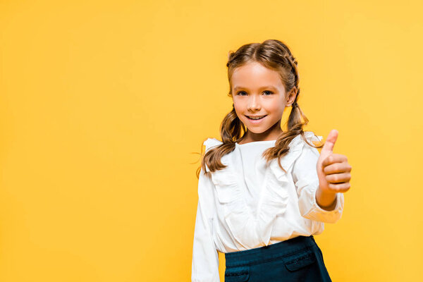 happy kid smiling and showing thumb up isolated on orange 