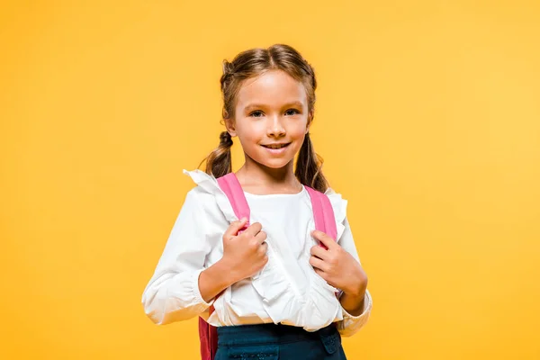 オレンジ色に孤立したピンクのバックパックに触れる幸せな小学生 — ストック写真