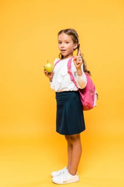 elma tutan ve turuncu üzerinde parmak ile işaret sevimli schoolkid 