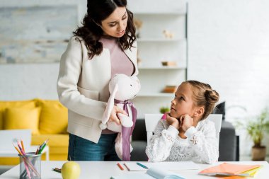 üzgün kızı yakın yumuşak oyuncak tutan çekici anne 