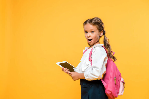 surprised schoolkid holding digital tablet with blank screen isolated on orange 