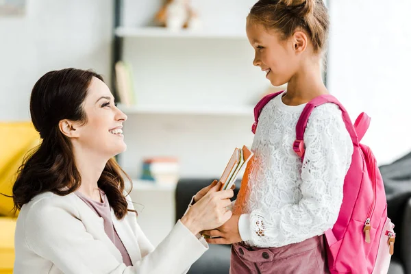 Feliz Madre Dando Libros Alegre Hija Casa —  Fotos de Stock