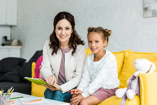 Mãe Feliz Segurando Livro Perto Filha Bonito Casa — Fotografia de Stock