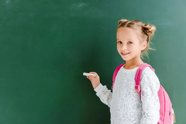Criança Escola Feliz Segurando Giz Perto Quadro Negro Verde — Fotografia de Stock