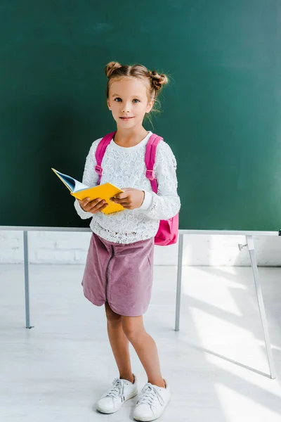 Happy Schoolkid Holding Book Green Chalkboard Classroom — Stock Photo, Image