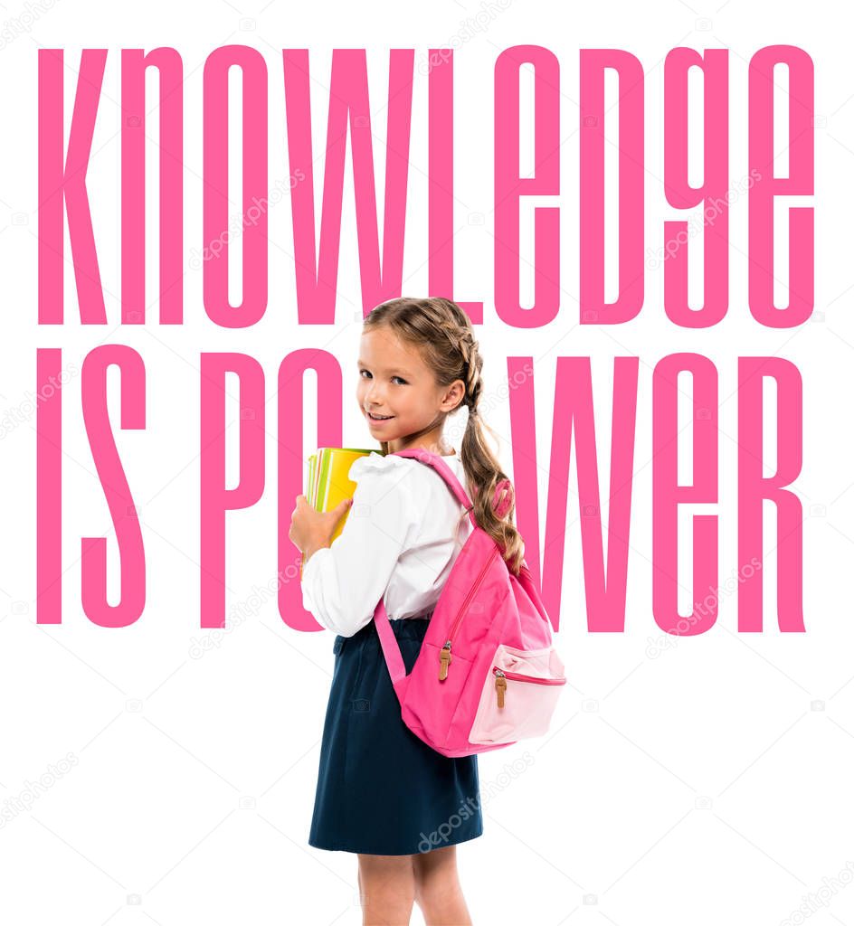 happy child holding books and standing with pink backpack near knowledge is power lettering on white 