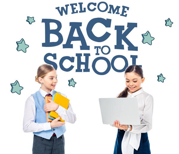 smiling schoolchildren in formal wear using laptop and holding books near welcome back to school letters on white 