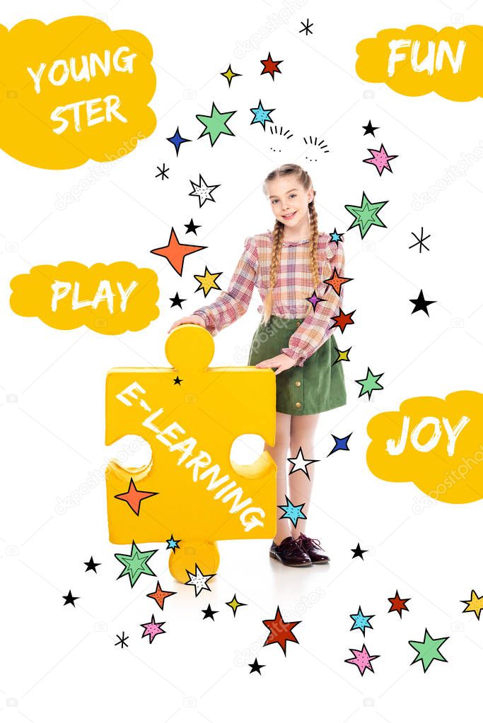 smiling kid with e-learning lettering on jigsaw puzzle piece looking at camera on white