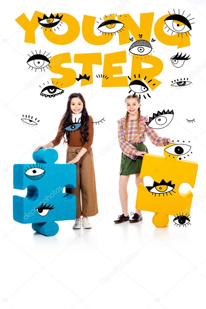 smiling kids with jigsaw puzzle pieces looking at camera near youngster lettering on white