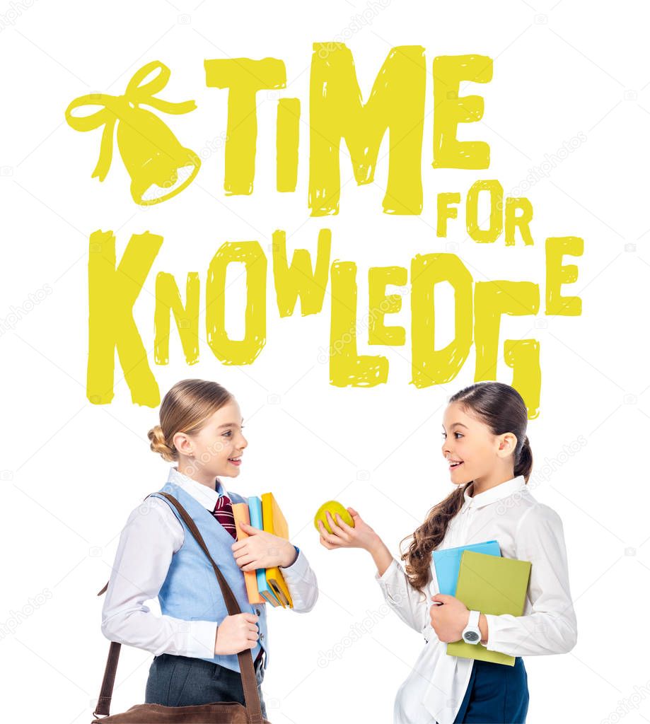 schoolgirls in formal wear with books and apple near time for knowledge letters on white 
