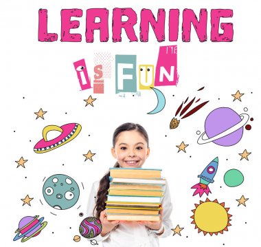 smiling schoolgirl holding books and looking at camera near learning is fun letters on white  clipart