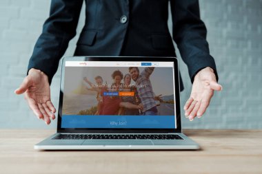 KYIV, UKRAINE - AUGUST 5, 2019: cropped view of woman gesturing near laptop with couchsurfing website on screen  clipart