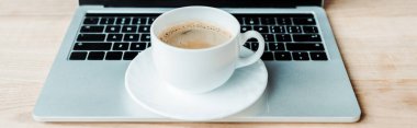 panoramic shot of cup of coffee on laptop in office  clipart