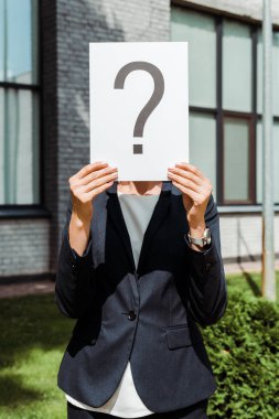 cropped view of woman holding placard with question mark near building  clipart