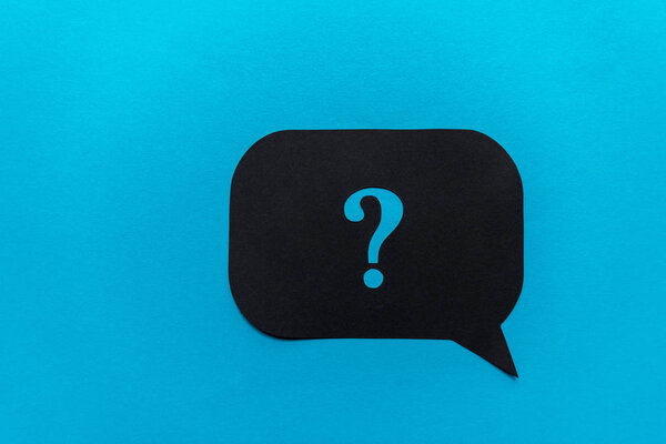 top view of of black question mark on speech bubble isolated on blue 