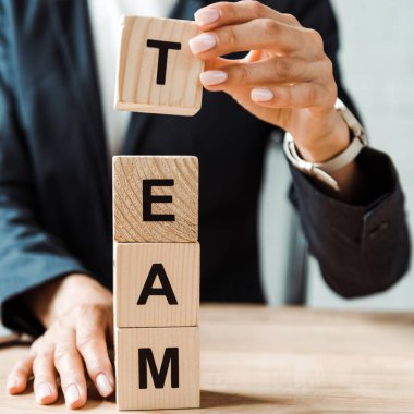 cropped view of businesswoman touching wooden cubes with team letters  clipart