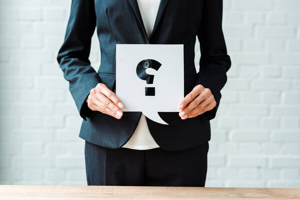 cropped view of woman holding speech bubble with question mark while standing in office 