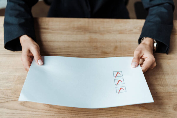 cropped view of woman holding paper with check list 