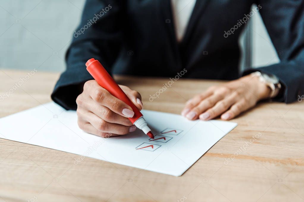 cropped view of businesswoman putting check park in check list 