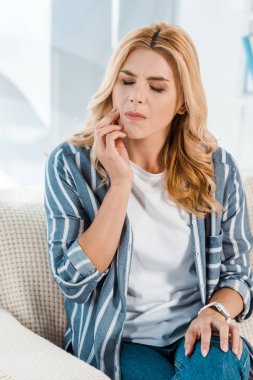 kanepede otururken diş ağrısı olan kapalı gözlü kadın 