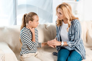 worried mother touching hand of sick daughter at home  clipart