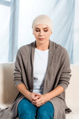 sick woman in head scarf sitting on sofa  clipart
