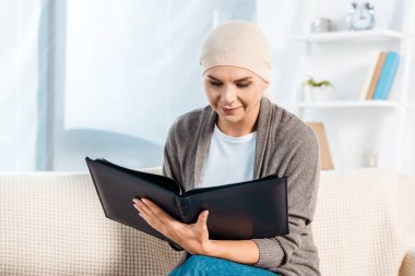 sick woman with head scarf holding photo album  clipart