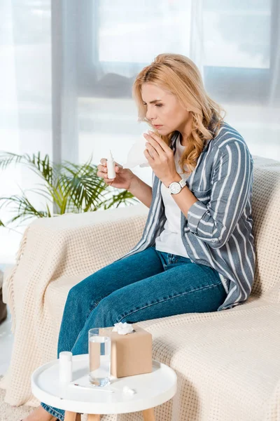 Kranke Frau Sitzt Auf Sofa Und Hält Nasenspray Und Gewebe — Stockfoto