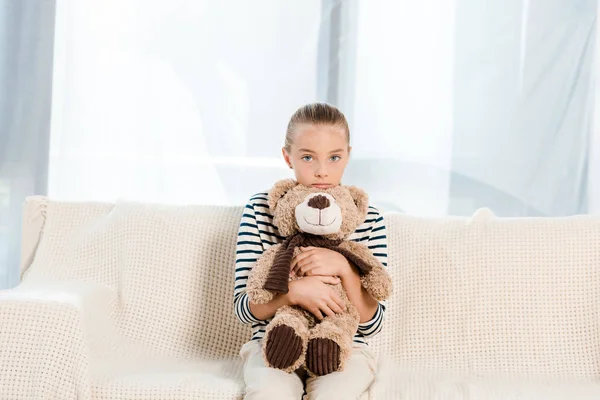 Cute Kid Holding Teddy Bear While Looking Camera Sitting Sofa — Stock Photo, Image