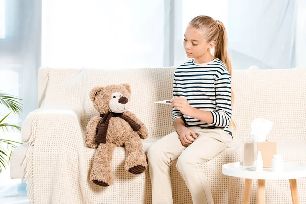 Kid Holding Digital Thermometer Teddy Bear Sitting Sofa — Stock Photo, Image