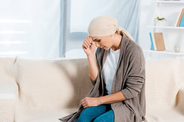 upset and sick woman with head scarf in living room 