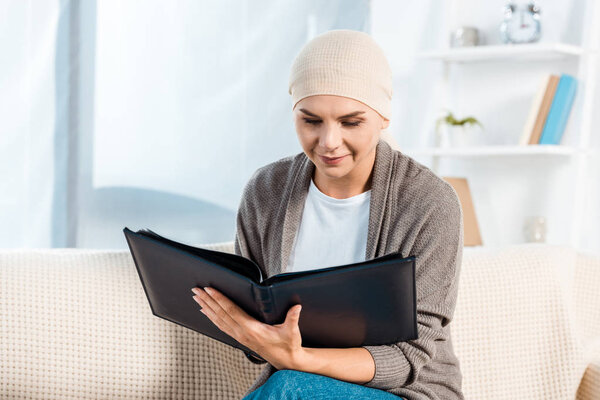 sick woman with head scarf holding photo album 