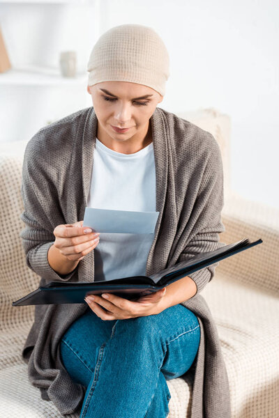 sick woman with head scarf holding photo in living room 